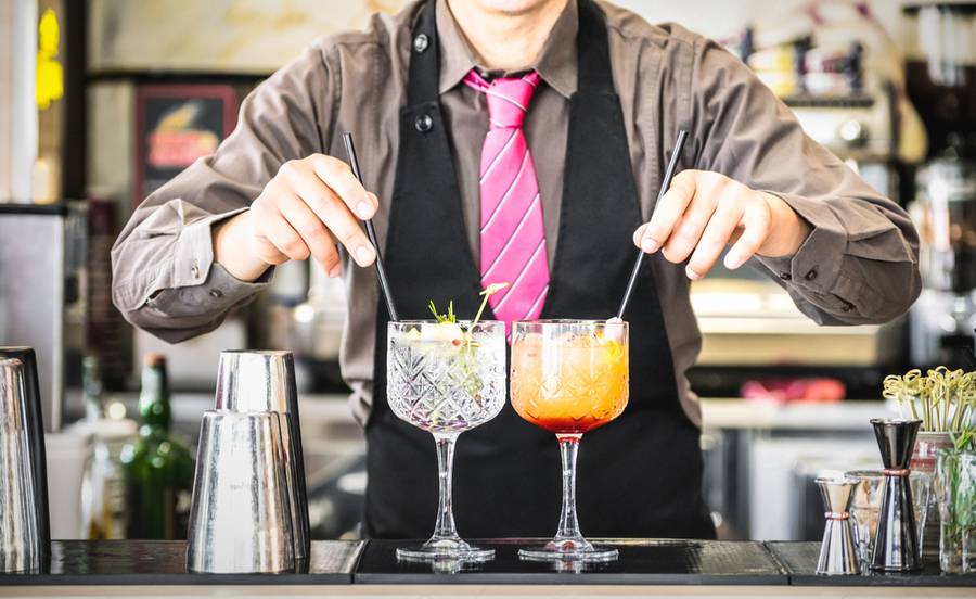 bartender serving gin tonic and tequila sunrise in california bar